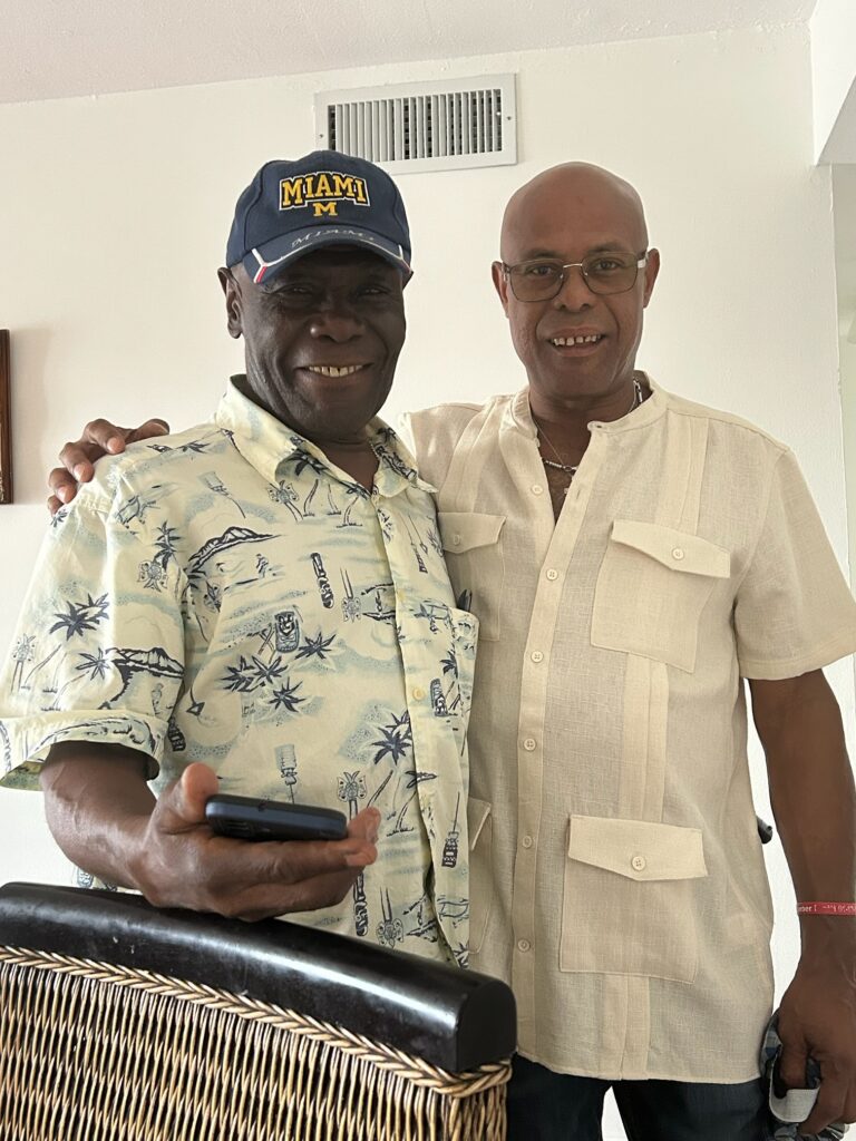 Two smiling men posing indoors together.